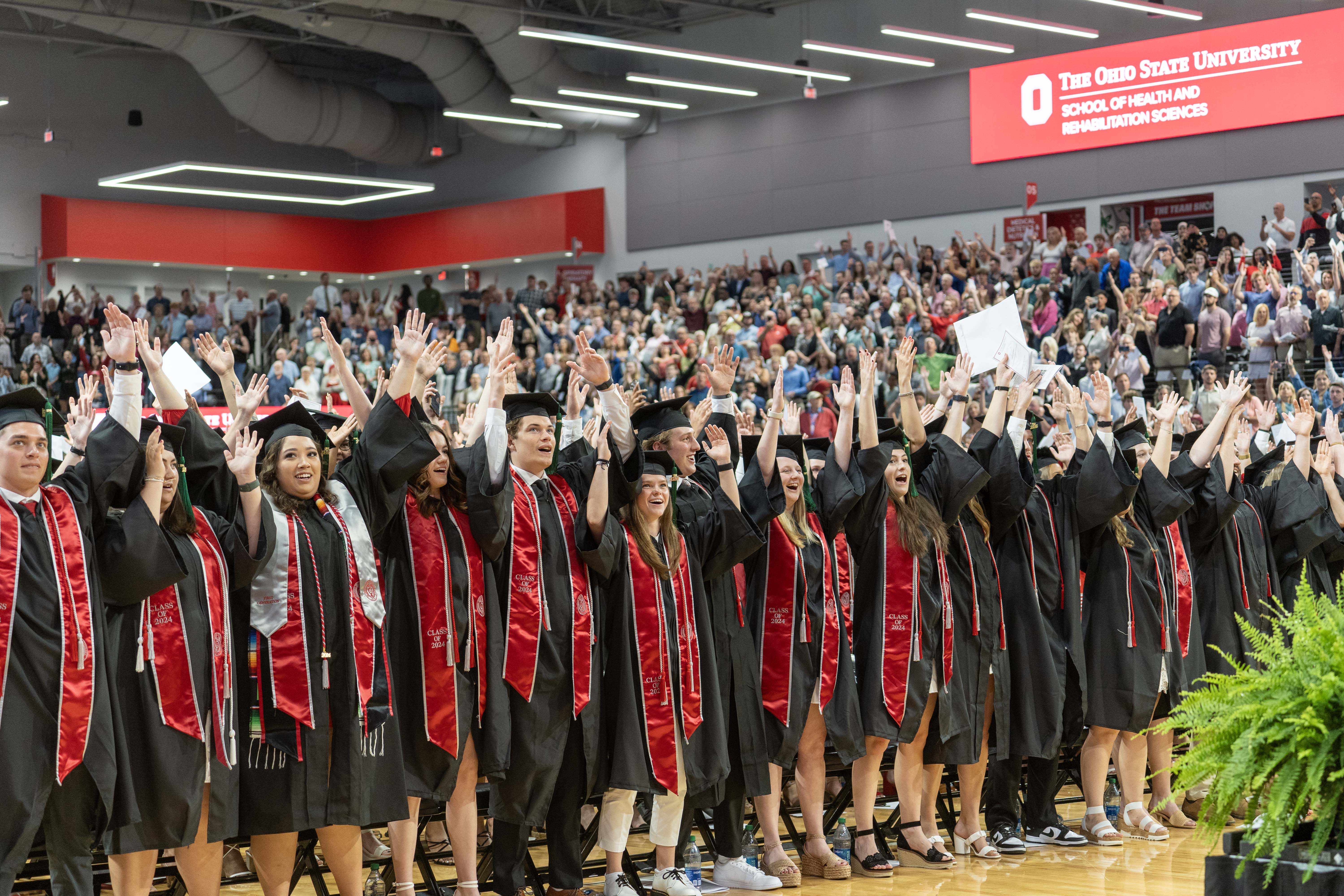 A group of graduates in caps and gowns at the pre-commencement ceremony inside the Covelli Center gymnasium, celebrating their academic achievements.
