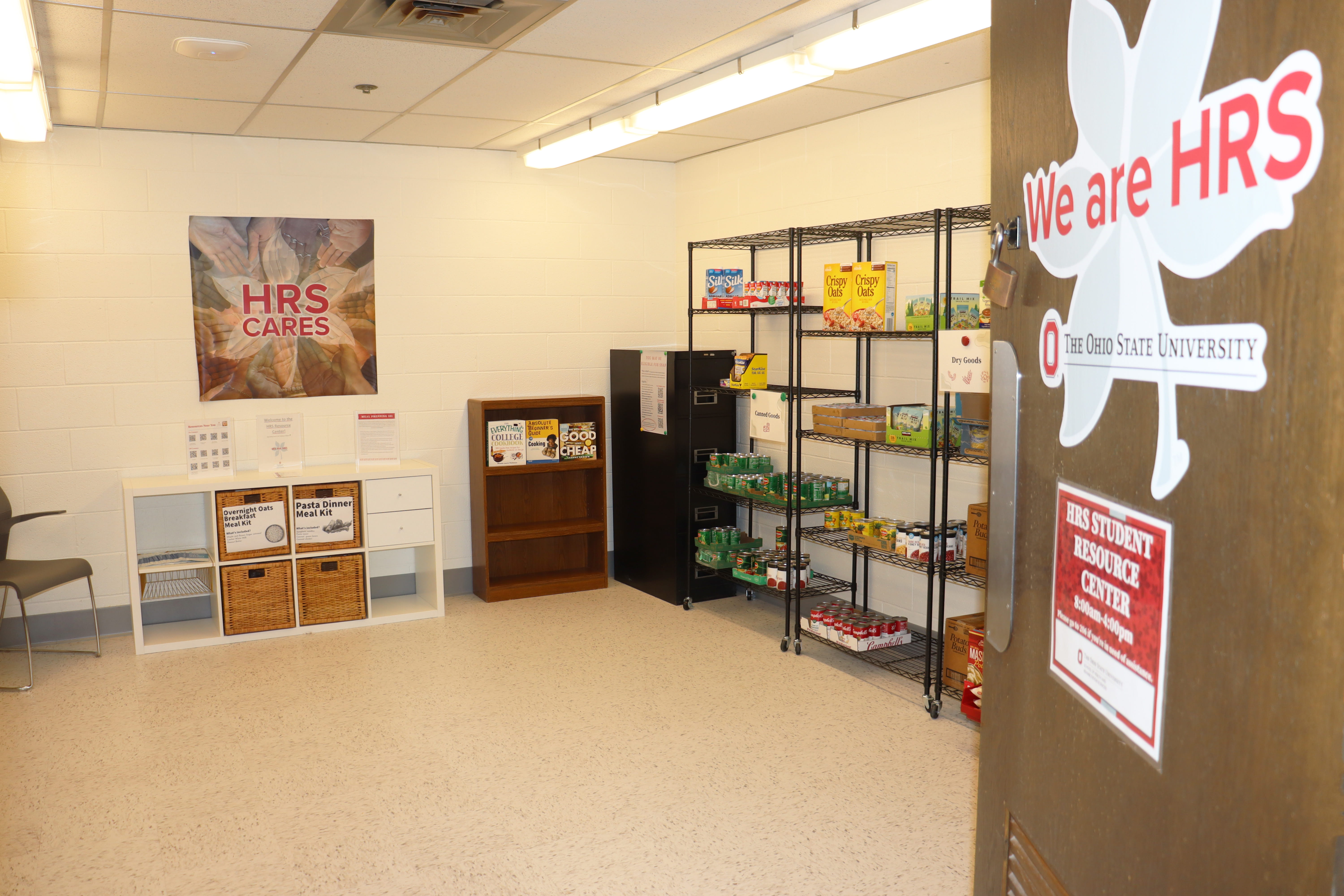 An image showing the interior of a student food pantry at The Ohio State University, featuring shelves stocked with food and personal care items, informational posters on the walls, and a sign that reads "We are HRS.