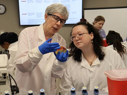 Medical Laboratory Science Professor showing a student a Petri dish