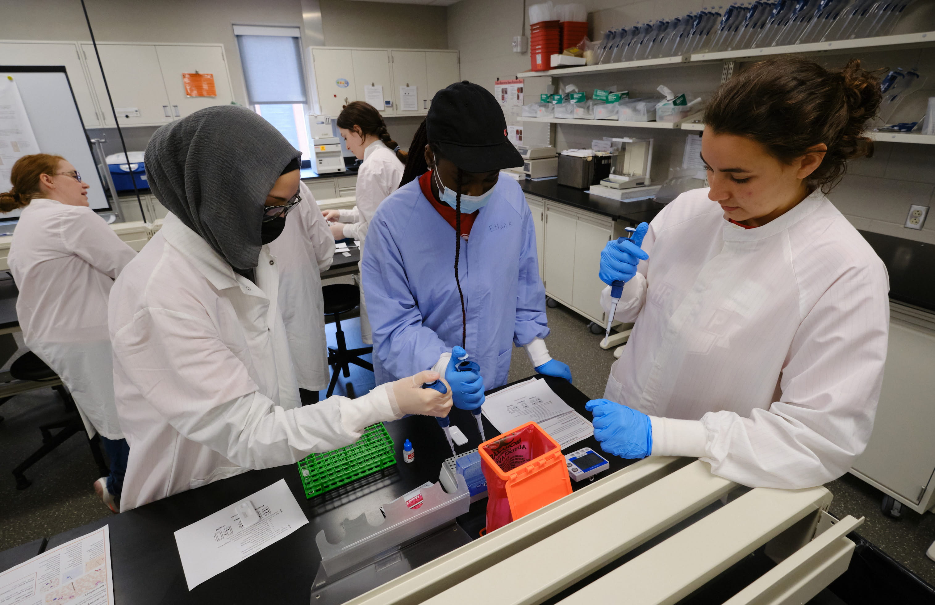 Students in lab coats using pipettes