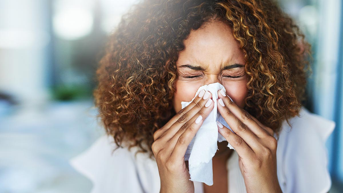 Black woman blowing her nose with a tissue
