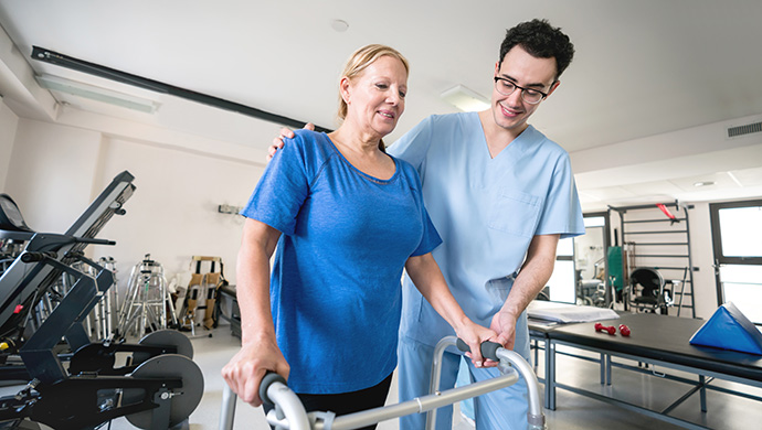 Physical therapist helping a woman use a walker